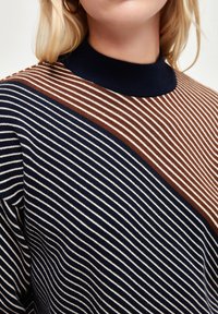 Sweter w paski o kolorystyce granatowej, brązowej i kremowej. Żebrowany kołnierz i ukośny wzór pasków tworzą wizualne zainteresowanie. Miękka tekstura.