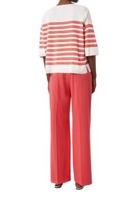 Gestreifter Strickpullover in Koralle und Weiß, kombiniert mit weiten Koralle-Hosen. Leicht und locker geschnitten, mit einer kastigen Silhouette und kurzen Ärmeln.