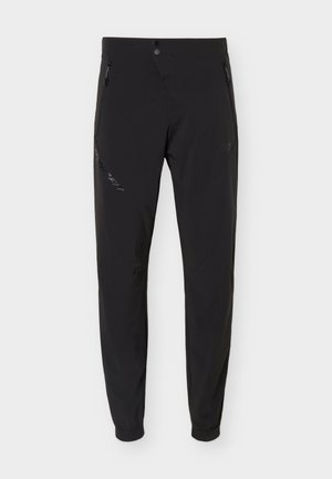 Black slim-fit outdoor pants with elastic cuffs, front button, and zippered side pockets, designed for active use.
