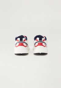 Sko med mesh tekstiloverdel som har røde og marineblå detaljer, polstret krage og en hvit såle med svart gummitread.