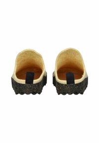 Par de pantuflas sin hebilla con parte superior de fieltro beige y suela texturada negra, vistas desde atrás sobre un fondo blanco.