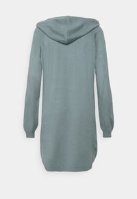 Långärmad, huva klädesplagg i mjukt, ljust tealfärgat tyg. Har en rundad nederkant och ribbade mudd. Slät textur med en avslappnad passform.