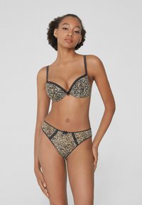 Ensemble de soutien-gorge et culotte en dentelle imprimée léopard avec des finitions noires. Le soutien-gorge présente un décolleté plongeant, des bretelles ajustables et un nœud central.
