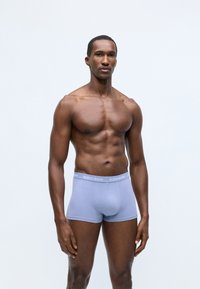 Ανοιχτό μπλε μποξεράκι από μαλακό ύφασμα με γκρι ζώνη που φέρει το λογότυπο "BJÖRN BORG". Το μοντέλο στέκεται σε ουδέτερη πόζα, αναδεικνύοντας την εφαρμογή.