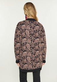 Černý cardigan s paisley vzorem v odstínech růžové a krémové, s ribovanými manžetami a lemem a volným střihem.