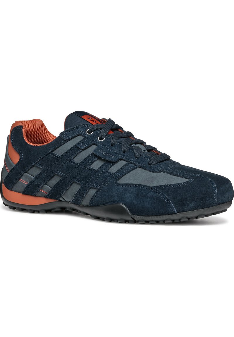 Zapatillas de ante azul marino con acentos de malla y cuero, presentan una suela de goma, cierre de cordones y detalles en naranja que contrastan.