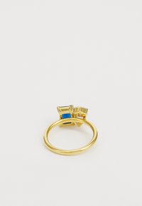 Anello d'oro con due pietre rettangolari, una blu e una trasparente, montate su prigionieri geometrici distintivi. Fascia liscia con finitura lucida.