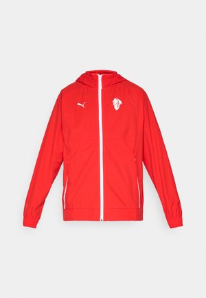 Czerwona lekka kurtka z kapturem, z zamkiem błyskawicznym, białymi akcentami oraz logo na klatce piersiowej i rękawie. Elastyczne mankiety i kaptur z regulacją.