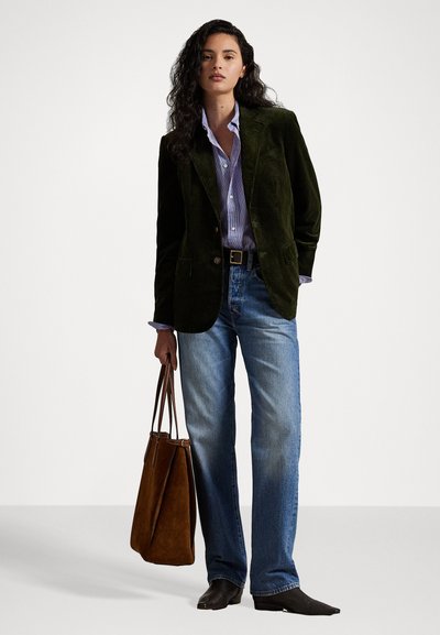 Dark green corduroy blazer, light blue striped shirt, light blue jeans, brown suede tote bag, black pointed shoes, standing on a white background.