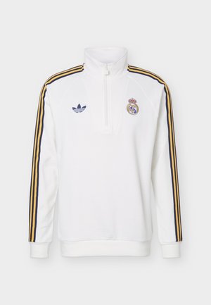 White long-sleeve sports pullover with half-zip, navy and gold shoulder stripes, Adidas and Real Madrid logos on the chest.