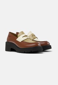 Bruine en beige leren loafers met een dikke zwarte plateauzool, met een dekoratieve band over de wreef en een afgeronde neus.