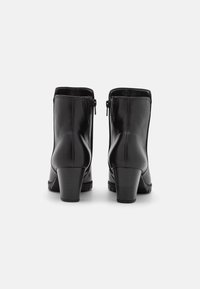 Černé kožené kotníkové boty s hladkou texturou, obdélníkovým podpatkem a bočními zipy. Nabízí elegantní design a minimalistické detaily šití.