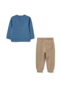 Pullover blu a maniche lunghe con chiusura a bottoni sul retro, abbinato a pantaloni jogger kaki con vita elastica e tasca laterale.