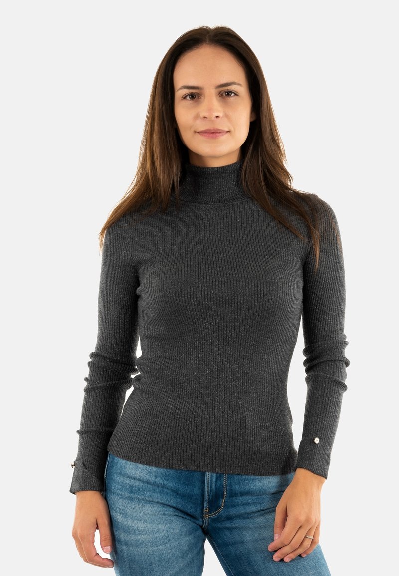 Maglione a collo alto grigio scuro a coste con maniche lunghe, caratterizzato da dettagli con bottoni sui polsini, abbinato a jeans in denim azzurro chiaro.