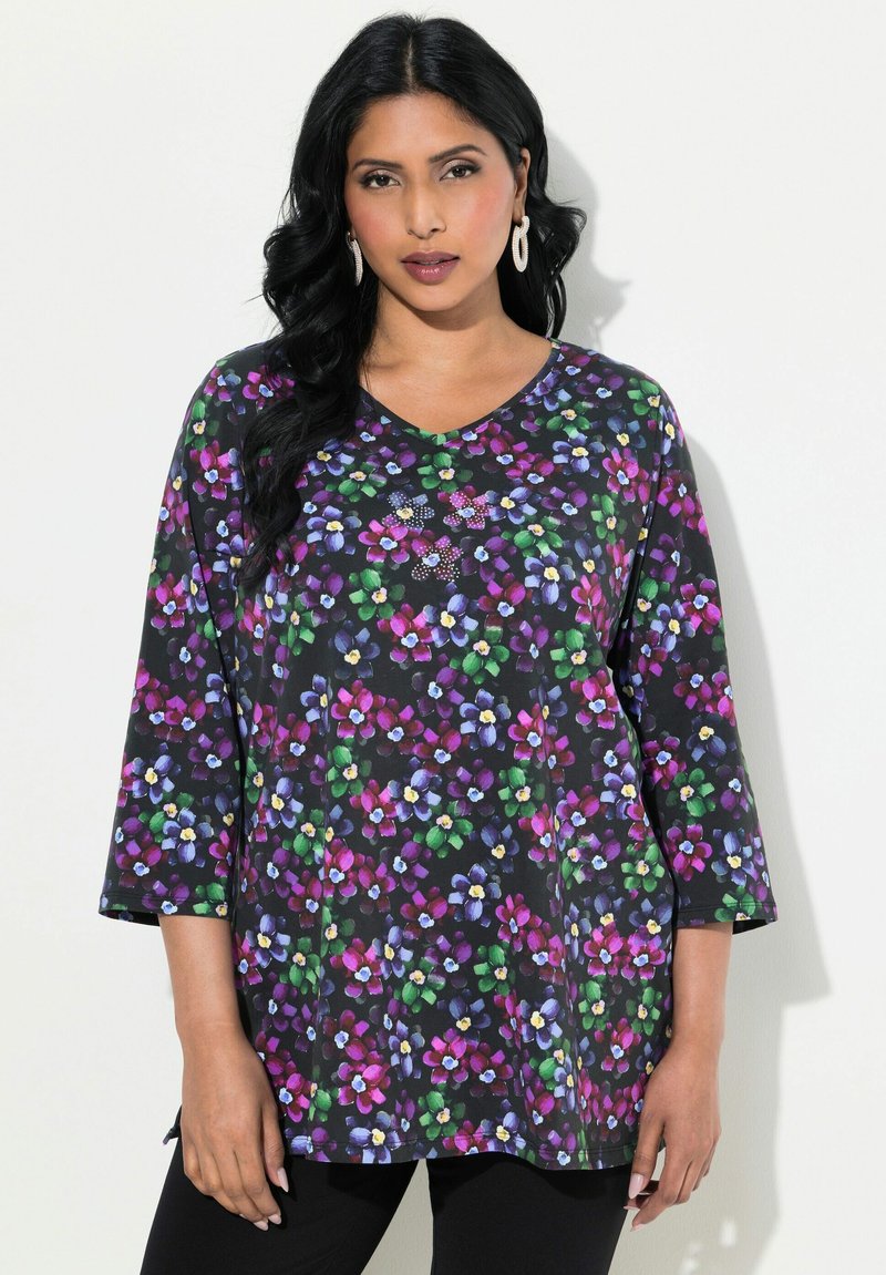 Camicia tunica floreale nera, con fiori multicolori in viola, verde e giallo. Scollo a V e maniche a tre quarti. Tessuto morbido.