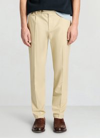 Pantalon beige à coupe ajustée, doté de doubles plis à l'avant et de deux boutons dorés à la taille, fabriqué dans un tissu lisse.