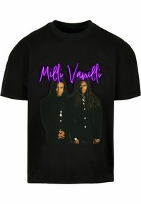 Must-su එක් tulee tumedate jakit palju kae mulgib. Tekst "Milli Vanilli" on piltist üleval heledates lillades tähtedes.
