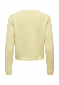 Gaiši dzeltena adīta džemperis ar gariem piedurknēm, apakšējā piedurkņu daļā raksturīga teksturēta raksta un apaļu kakla izgriezumu.