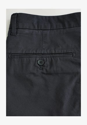 Schwarze Baumwollhose mit einer Gesäßtasche und Knopfverschluss, glatter Textur und sauberen Nähten.