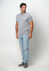 Grå kortärmad pikétröja med krage och två knappar, kombinerad med ljusblå jeans och grå sneakers. Enkla mönster, mjuk textur.