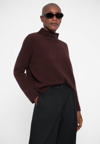 Burgundi värvi villane kõrge kaelusega sviiter, millel on mugav lõige, koos kõrge vöökohtadega mustade pükstega. Sviiteril on pikad varrukad ja pehme tekstuur.