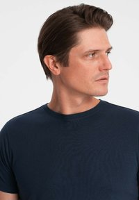 Námorně modré tričko s kulatým výstřihem vyrobené z měkké bavlny, s hladkou strukturou a přiléhavým střihem. Minimalistický design bez viditelných vzorů.