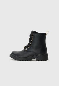 Bottine en cuir noir avec œillets dorés, conception à lacets, bout arrondi et semelle robuste, dotée d'une languette à l'arrière.
