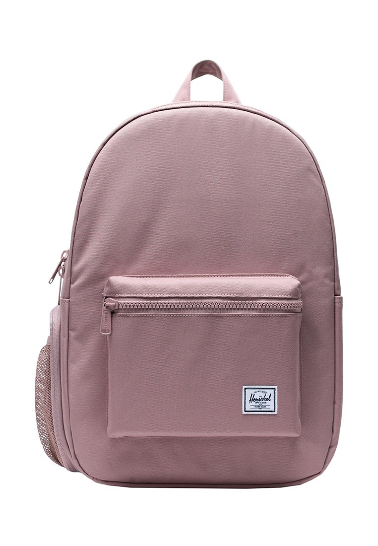 Rosa Stoffrucksack mit runder Form, ausgestattet mit einer vorderen Reißverschlusstasche, einer seitlichen Netztasche und einem oberen Griff für einfaches Tragen.