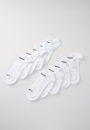 Hvite ankelstrømper arrangert i to rader, med svarte striper på toppen, laget av mykt stoff med teksturerte såler for grep.