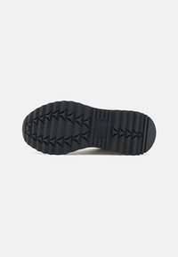 Suola di scarpa in gomma nera con texture rigata e battistrada triangolari, progettata per la trazione e la durata.