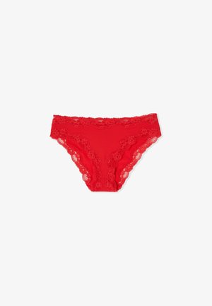 Sous-vêtement féminin style bikini rouge orné de dentelle avec des motifs floraux le long de la ceinture et des ouvertures pour les jambes sur fond blanc.