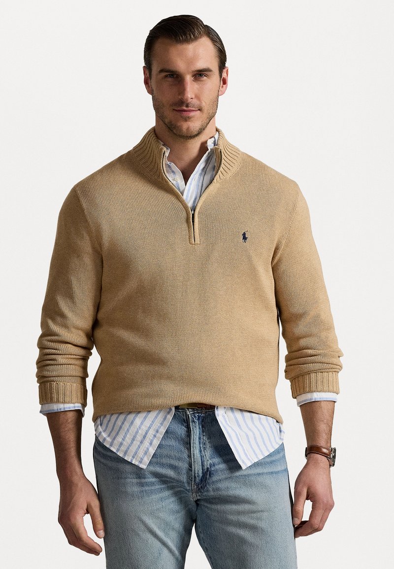 Beige stickad tröja med hög krage och dragkedja, med ribbade mudd. Buren över en blå och vit randig skjorta med en avslappnad passform.