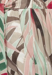 Tropical print fabric featuring large, abstract leaves in green, pink, and brown tones. Material has a smooth, slightly textured finish.