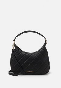 Black quilted handbag with a structured shape, featuring a top zipper, short handle, and gold logo detail on the front. Smooth texture.