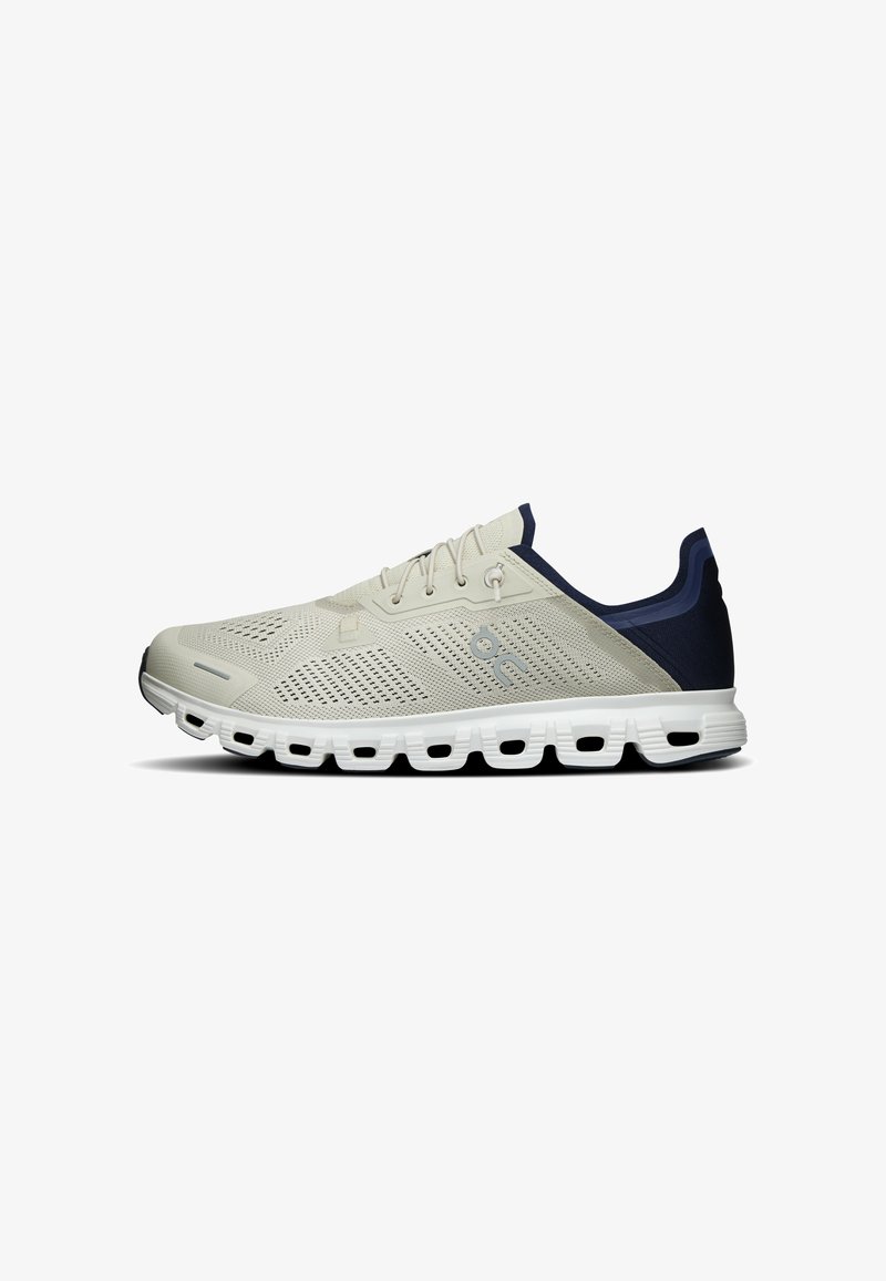 Chaussure de running gris clair avec une tige en mesh respirant, une semelle blanche segmentée et un col de talon bleu foncé, vue de profil.