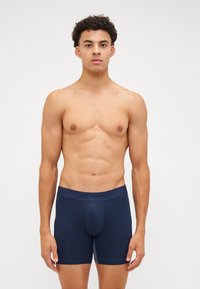 Navy boxer briefs made of smooth fabric with a branded elastic waistband. Features a fitted design and short leg length.