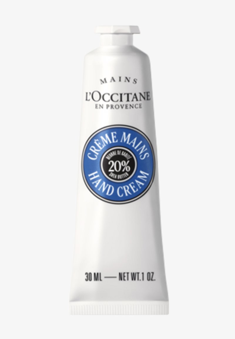 Crema per le mani L'Occitane in un tubetto bianco da 30 ml, con un'etichetta circolare blu con la scritta "20% burro di karité" e "CRÈME MAINS". Tappo a chiusura a scatto.