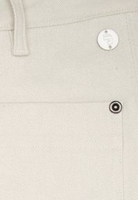 Witte katoenen broek met een textuurlafwerking, voorzien van een metalen logo-knop en een drukknoopzak met een zwart metalen accent.
