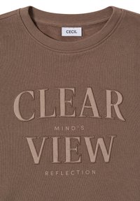 Sweatshirt marron avec un col rond, tissu texturé et texte brodé : "REFLET D'ESPRIT CLAIR" en couleurs contrastées.