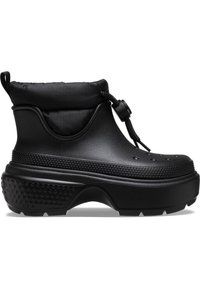 Botas negras hasta el tobillo con un puño acolchado, hechas de un material similar al caucho. Presentan acentos texturizados y una suela gruesa con dibujo para un mejor agarre.