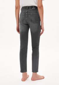 Jean en denim gris à coupe slim, avec une taille mi-haute et un design classique à cinq poches. Comprend une étiquette logo sur la ceinture arrière.
