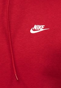 Κόκκινο ύφασμα με κεντητό λογότυπο Nike σε λευκό χρώμα και κόκκινο κορδόνι που ταιριάζει.
