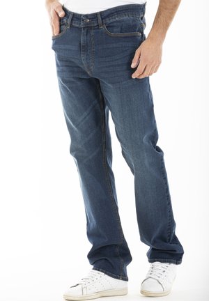 Jean en denim bleu avec une coupe droite, accents de couture visibles et design à cinq poches. Assortis à des baskets blanches de sport.