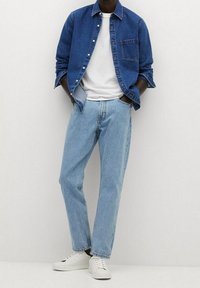 Denim overhemden in diepblauw, witte T-shirt, lichtblauwe rechte jeans en witte sneakers. Eenvoudige en casual outfit.