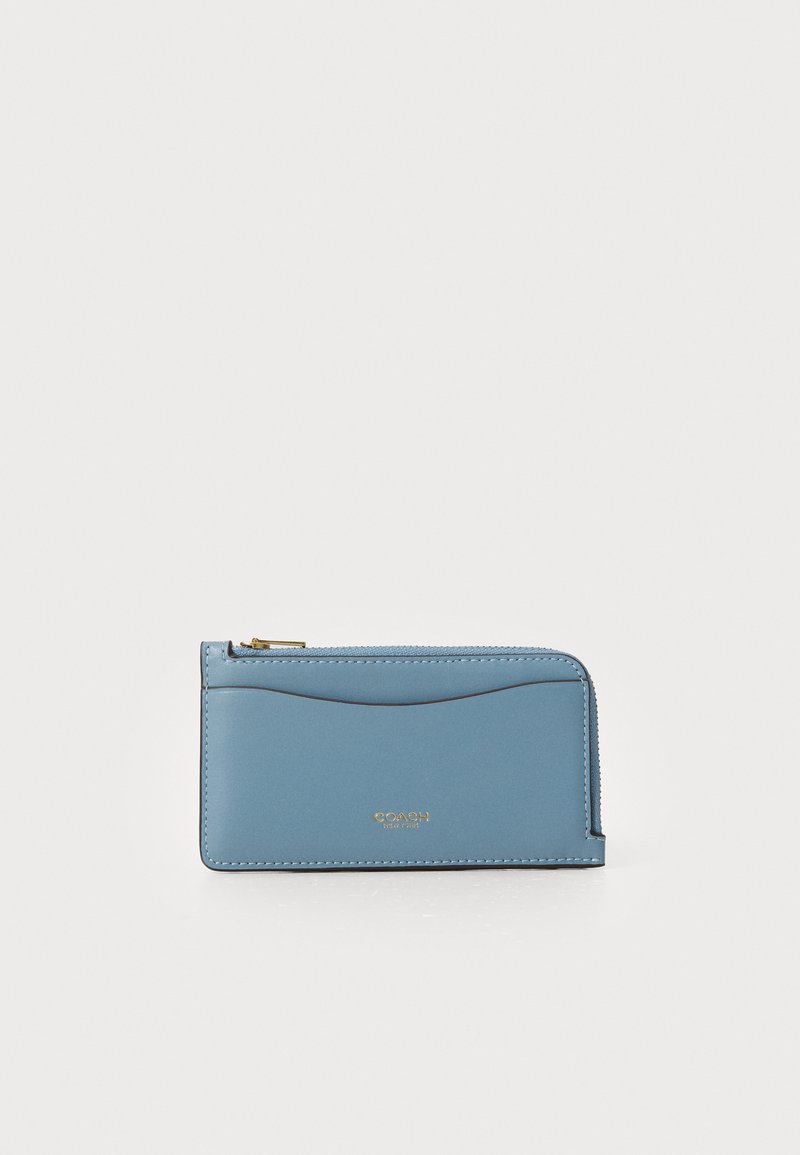 Cartera de cuero azul con herrajes dorados, cierre de cremallera y textura suave. Presenta detalles de costura y un logo sutilmente grabado.