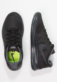 Scarpe da ginnastica nere Nike con tomaia in rete, design testurizzato e soletta verde a contrasto, dotate di una suola in gomma liscia e sistema di allacciatura.
