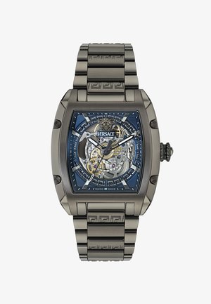 Versace laikrodis su stačiakampiu sidabriniu korpusu, mėlynu raštuotu ciferblatu, atskleidžiančiu sudėtingas pavaras, ir derančiu metaliniu apyrankiu.