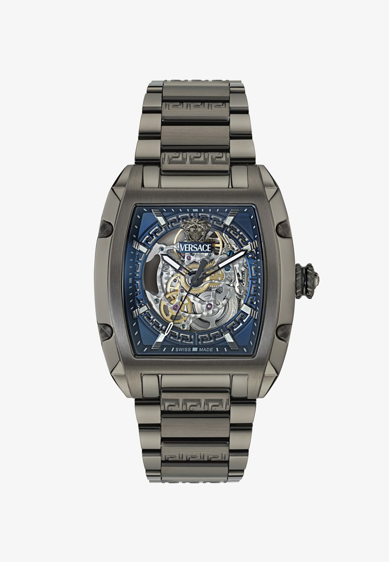 Reloj Versace con caja rectangular de plata, esfera azul con patrón que revela engranajes intrincados y un brazalete metálico a juego.