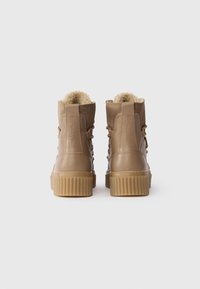 Barna műbőr bokacsizmák texturált felülettel, puha béléssel és bordázott gumitalppal. Fűzős kialakítás és logó részlet a saroknál.