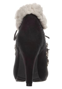 Scarpa nera in suede con tacco alto, con un bordo superiore bianco e soffice, punta affusolata e hardware decorativo in argento di lato.